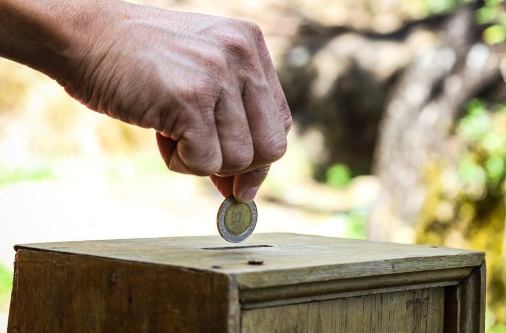 stock photo a man hand putting coin into a wooden box as donation 562231642 transformed